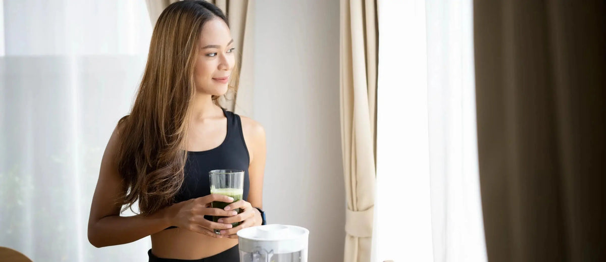 A woman drinking a smoothie wondering about the signs of the heavy metal detox working